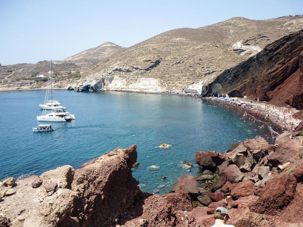 Red volcanic cliffs above a small sandy cove at Red Beach in Santorini, Greece